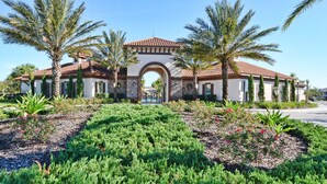 A building with a central arched entrance, surrounded by palm trees and landscaped gardens.