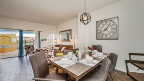 A dining area with a wooden table set for four, surrounded by chairs. A large wall clock and a mirror are visible. - Newly Renovated, Spacious 3bd/2.5ba Villa With Lake View, Near Disney #3tv709 (Kissimmee)