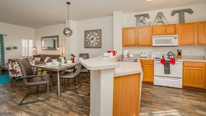 A modern kitchen with wooden cabinets, a white countertop, and a microwave. There is a dining area with a table and chairs, and a large mirror on the wall. - Newly Renovated, Spacious 3bd/2.5ba Villa With Lake View, Near Disney #3tv709 (Kissimmee)