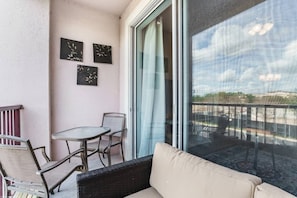 Relax on the balcony with a round table and two chairs, offering a view of the outdoor space through the glass door.
