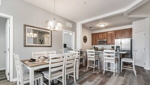 A modern kitchen with white cabinetry, a central island, and a dining area with white chairs. - Roomy and Modern 3bd/2ba Home With Balcony #3vc201 (Orlando)