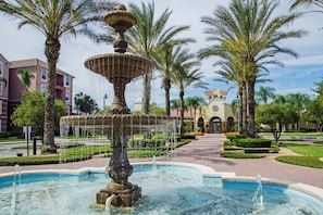 Stunning garden oasis with a beautifully maintained fountain and arched building in the background.