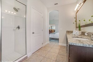 A modern bathroom with a glass shower enclosure, a vanity with a granite countertop, and a large mirror.