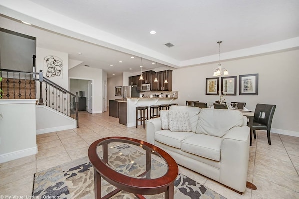 A spacious living room with a white sofa, a round coffee table, and a staircase leading to an upper level.