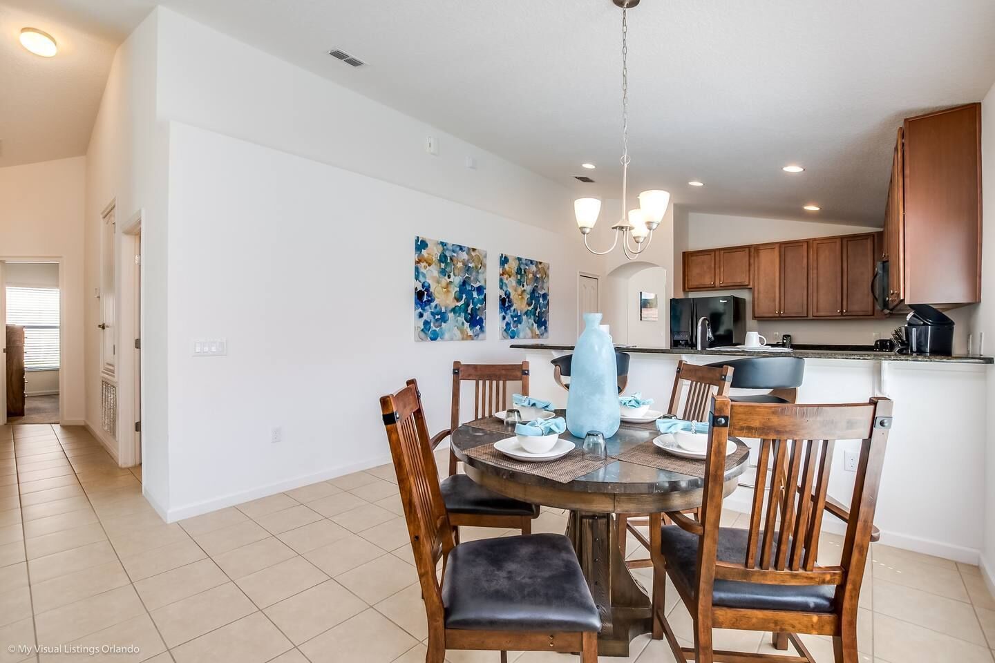 A dining area with a round table, wooden chairs, and a chandelier.