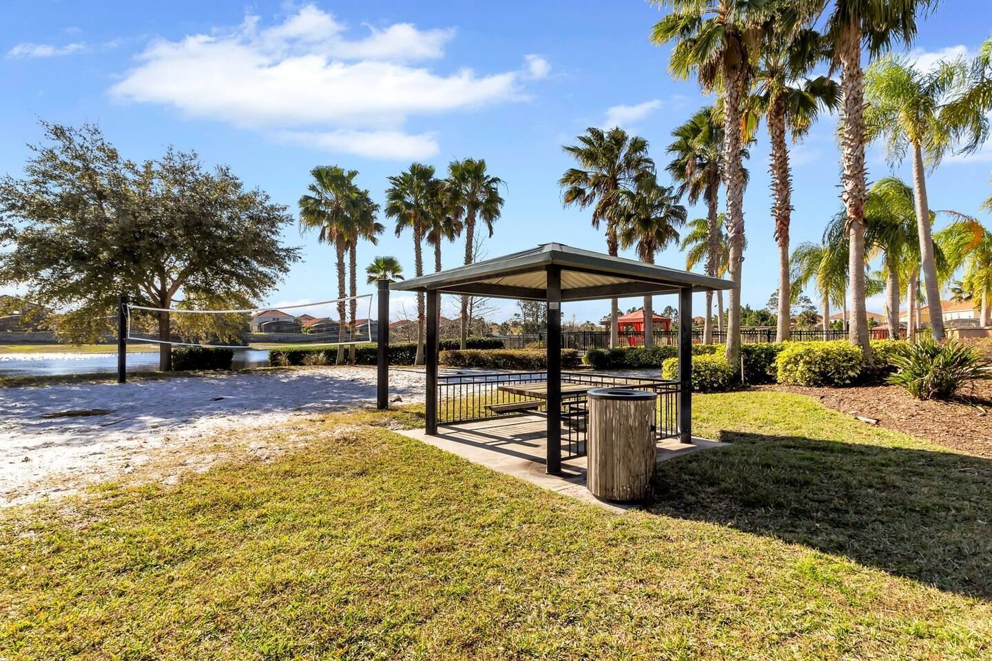 A gazebo with a metal railing, surrounded by palm trees and a grassy area.