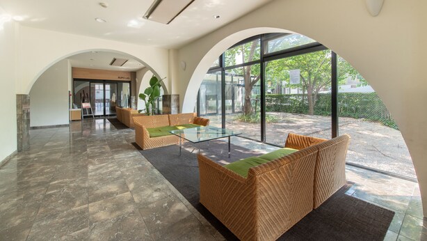 A modern lobby with a glass coffee table, wicker sofas, and a view of the outdoors. - Rupo Kenchoguchi Cozy Hotel (Fukuoka)
