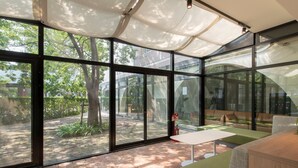 A modern interior with large glass windows, a brick floor, and a green sofa. - Rupo Kenchoguchi Cozy Hotel (Fukuoka)
