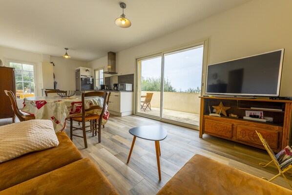Ein geräumiger Wohnbereich mit Sofa, kleinem Tisch, Fernseher und Balkon mit Blick.