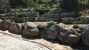 Un sendero de piedra que atraviesa un jardín con grandes rocas y un muro de piedra.