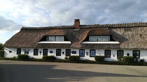 A traditional thatched-roof building with a white facade, multiple windows, and a sign indicating the year 1788.
