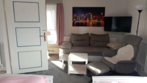 A living room with a sofa, a television, and a door with a lock.