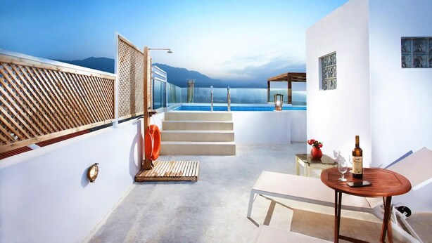Une terrasse sur le toit avec une piscine, des sièges extérieurs et une vue sur les montagnes.