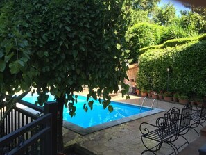 A swimming pool surrounded by lush greenery and potted plants. - Le Querce (Formello)