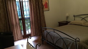 A bedroom with a bed, a nightstand, a lamp, and a poster on the wall. - Le Querce (Formello)