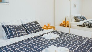 Un lit bien fait, recouvert d’une couverture à carreaux bleus et blancs, avec deux oreillers et une paire de serviettes blanches posées sur le lit.