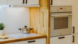 Une cuisine avec des meubles blancs, un plan de travail en bois et une cuisinière.