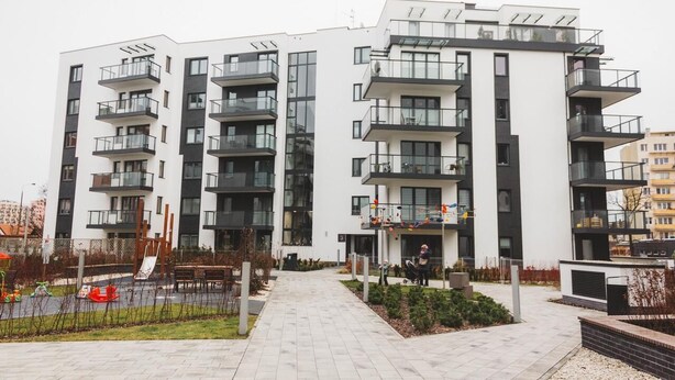 Un immeuble d’appartements moderne doté de nombreux balcons, d’une cour intérieure et d’un espace de jeux pour enfants.