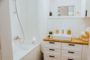 Comfort studio suite | Badkamer | Een bad/douchecombinatie, een haardroger, handdoeken, zeep