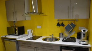 Eine Küche mit weißer Arbeitsplatte, Spüle aus Edelstahl und einer Kaffeemaschine.