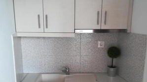 A kitchen with white cabinets, a sink, and a small potted plant. - Vaya Zorba Studios (Skiathos)