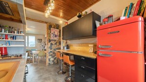 A kitchen with a red refrigerator, wooden cabinets, and a stone wall. - Back to the 80'S Apartment (Saint-Egrève)