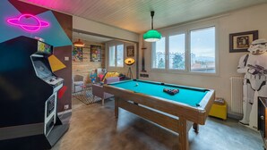 A pool table in a room with a neon sign, a space-themed wall, and a Star Wars figure. - Back to the 80'S Apartment (Saint-Egrève)
