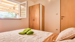 A bedroom with a bed, a wooden wardrobe, and a window with a view of greenery. - Casa Oliveto - relax in Nature (Marčana)