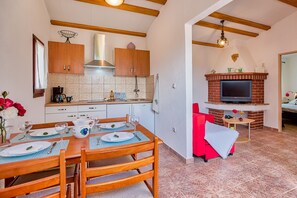 A kitchen with wooden cabinets, a stove, and a dining area with a table set for two.