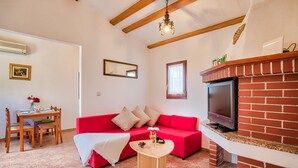 A living room with a red sofa, a TV, a fireplace, a dining table with chairs, and a chandelier. - Casa Oliveto - relax in Nature (Marčana)
