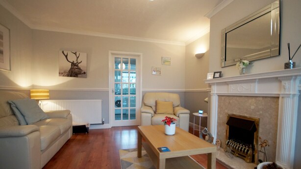 Een woonkamer met een bank, een salontafel, een open haard en een deur naar een andere kamer.