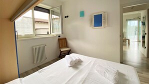 A bedroom with a bed, a window, a radiator, and a chair. - Gardenia Apartment Ossuccio (Ossuccio)