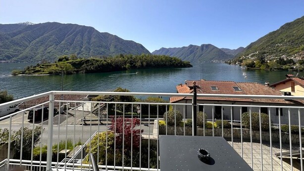 A balcony with a view of a lake, mountains, and a small island. - Gardenia Apartment Ossuccio (Ossuccio)