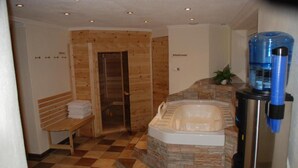 A bathroom with a stone wall, a bench, a shower, and a water dispenser. - Tirol apartment with 2 bedrooms (Mayrhofen)