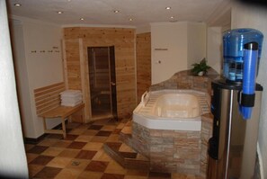 A bathroom with a stone wall, a bench, a shower, and a water dispenser.