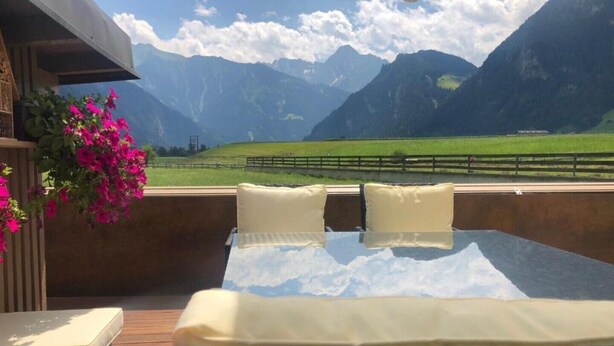 A balcony with a bed, pillows, and a view of mountains. - Tirol apartment with 2 bedrooms (Mayrhofen)