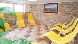 A room with a checkered floor, yellow-striped lounge chairs, a stone wall, and a framed picture. - Tirol apartment with 2 bedrooms (Mayrhofen)