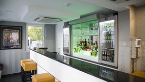 Un espace bar doté d’un long comptoir, de tabourets et d’étagères remplies de bouteilles.