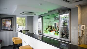 Eine Bar mit einer langen Theke, Barhocker und Regalen voller Flaschen.