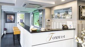 Un espace d’accueil comprenant un comptoir, des tabourets de bar, un bureau de réception, un miroir reflétant le paysage urbain et un tableau encadré accroché au mur.