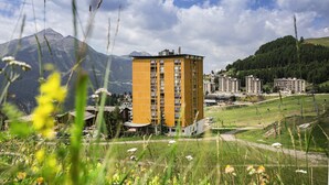 A multi-story building with a modern design, surrounded by a mountainous landscape and a clear sky. - Belambra Clubs Orcières 1850 - Le Roc Blanc (Orcieres)