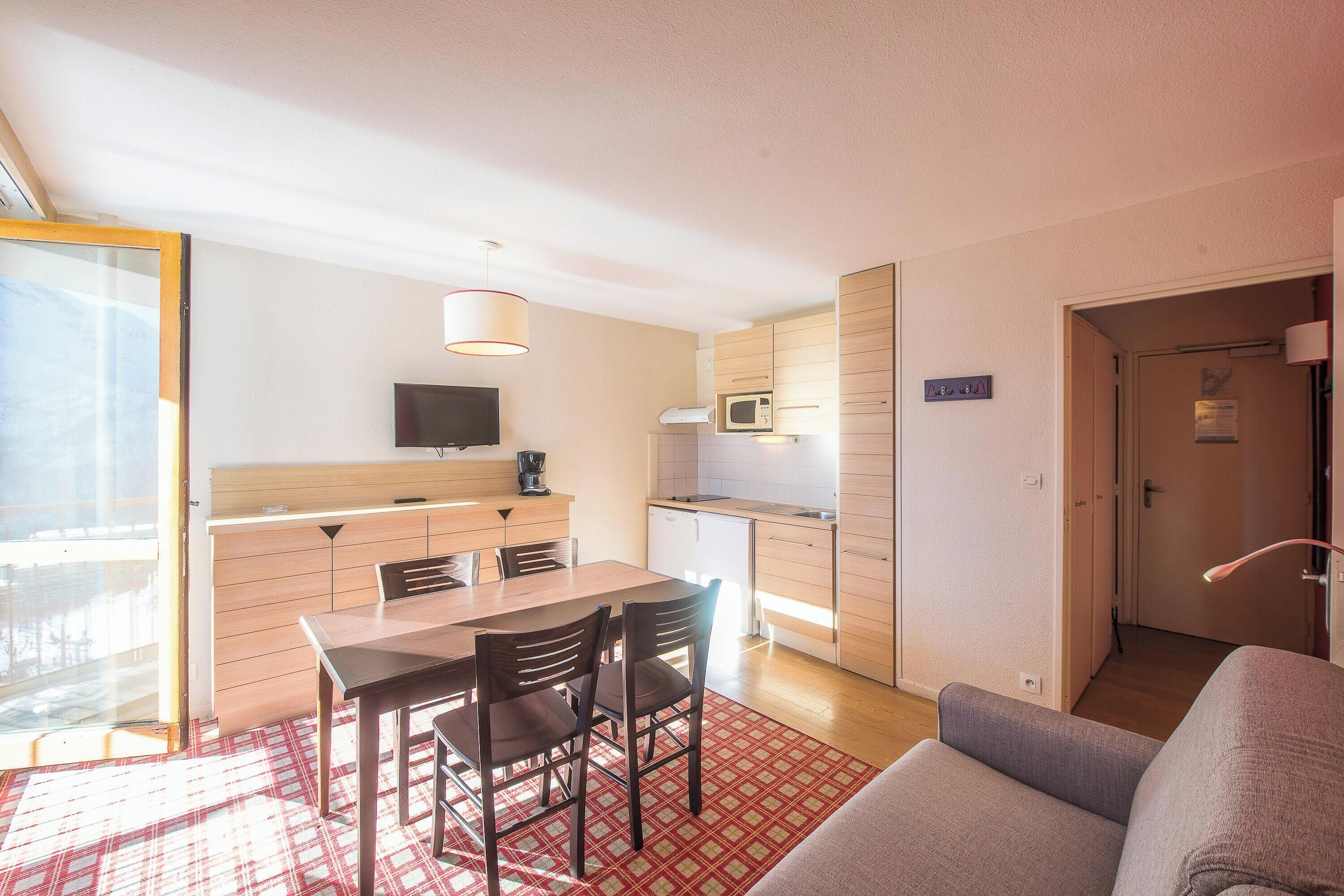 Un espacio habitable compacto con comedor, kitchenette y sofá.