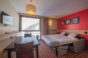 A hotel room with a bed, a desk, a chair, a TV, and a window with curtains. - Belambra Clubs Orcières 1850 - Le Roc Blanc (Orcieres)