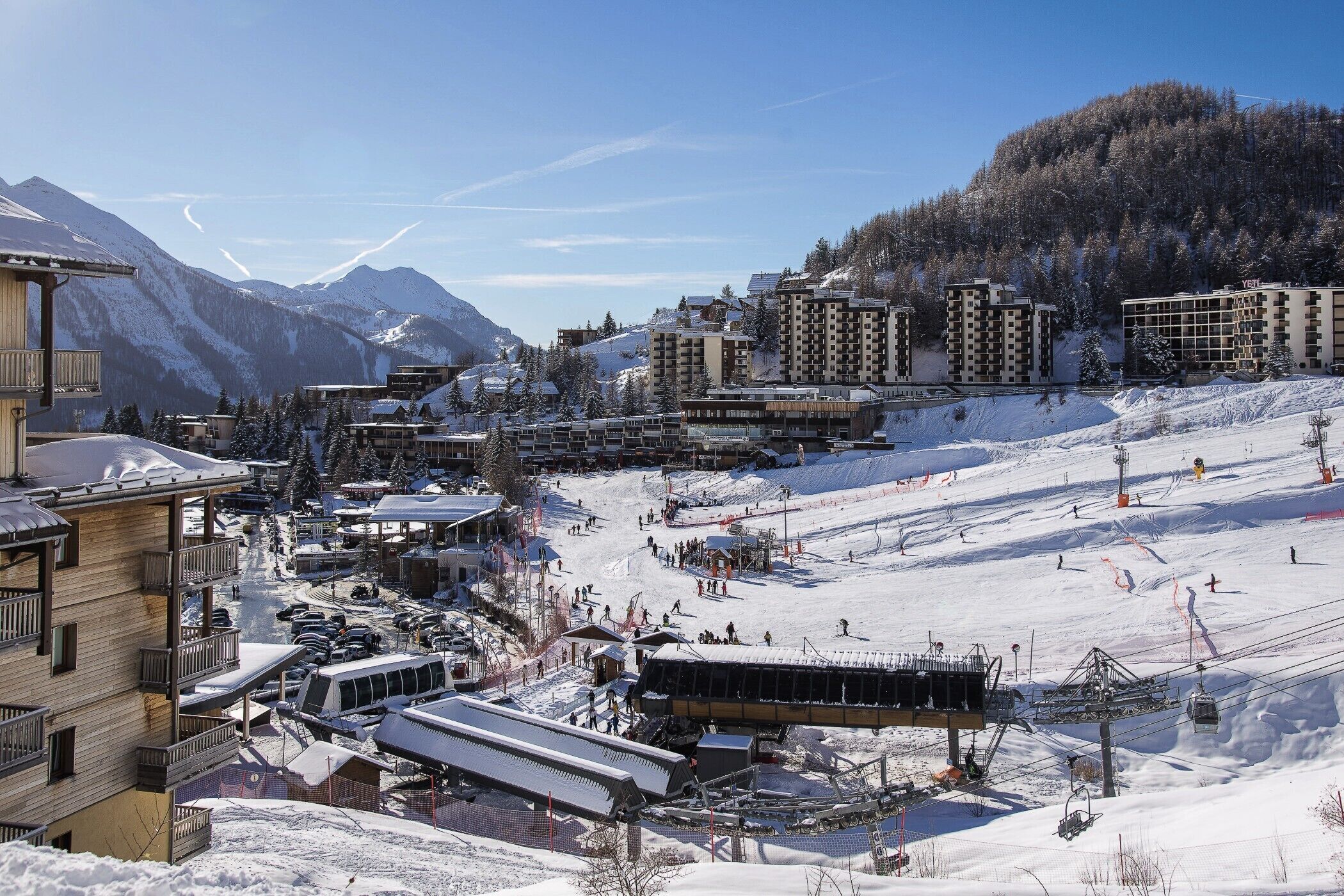 A ski resort with multiple buildings, a ski lift, and a snowy landscape.