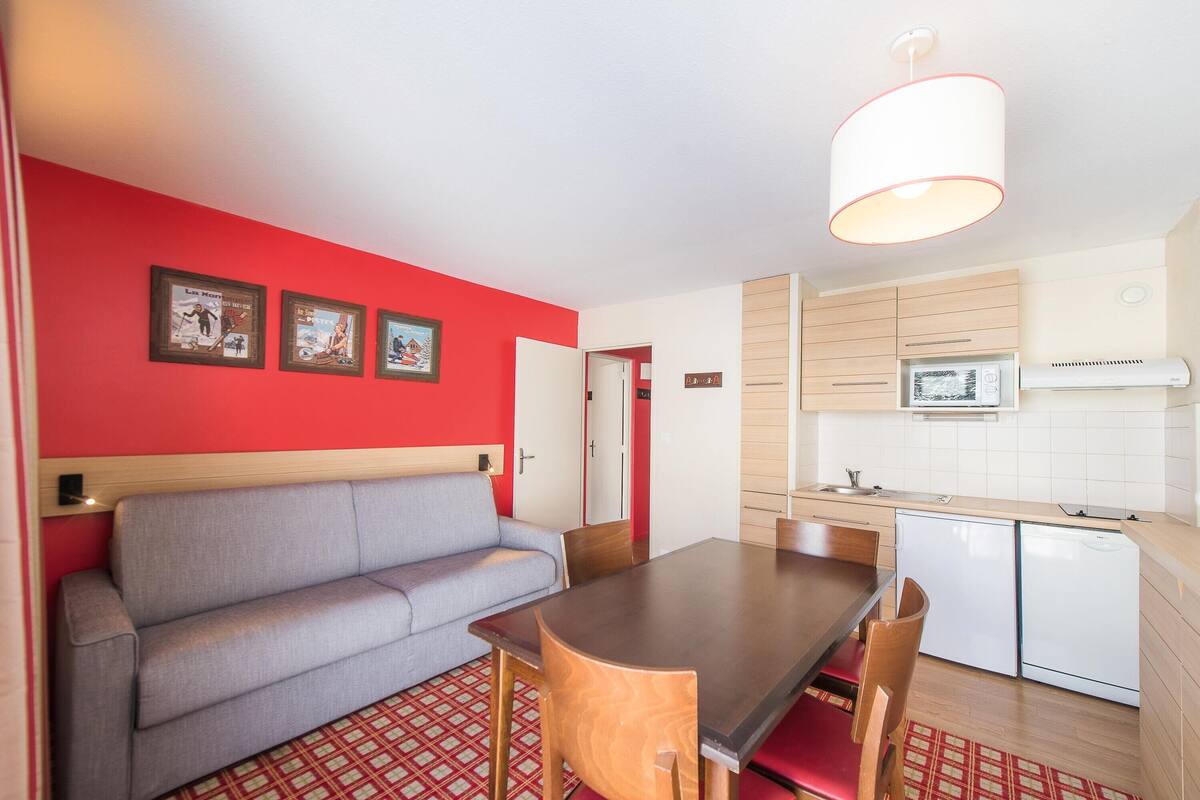 A compact living space with a kitchenette, a dining area, and a sofa.