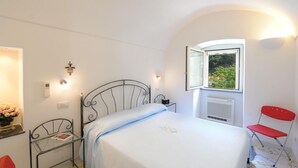 Une chambre à coucher avec un lit, une fenêtre, un radiateur, une chaise rouge et une table de chevet avec une lampe.