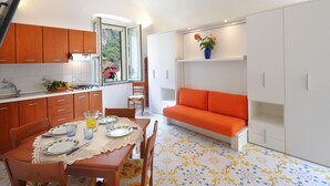 Une cuisine compacte avec des meubles en bois, une table à manger pour deux personnes et un canapé orange vif.