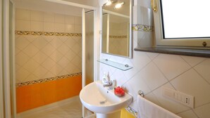 Une salle de bain avec un lavabo blanc, un miroir et un espace douche.