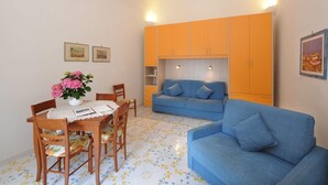 Un espace de vie compact comprenant un coin repas, un canapé et une kitchenette.