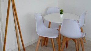 Un comedor con una mesa redonda y cuatro sillas, una lámpara de pie y un reloj en la pared.